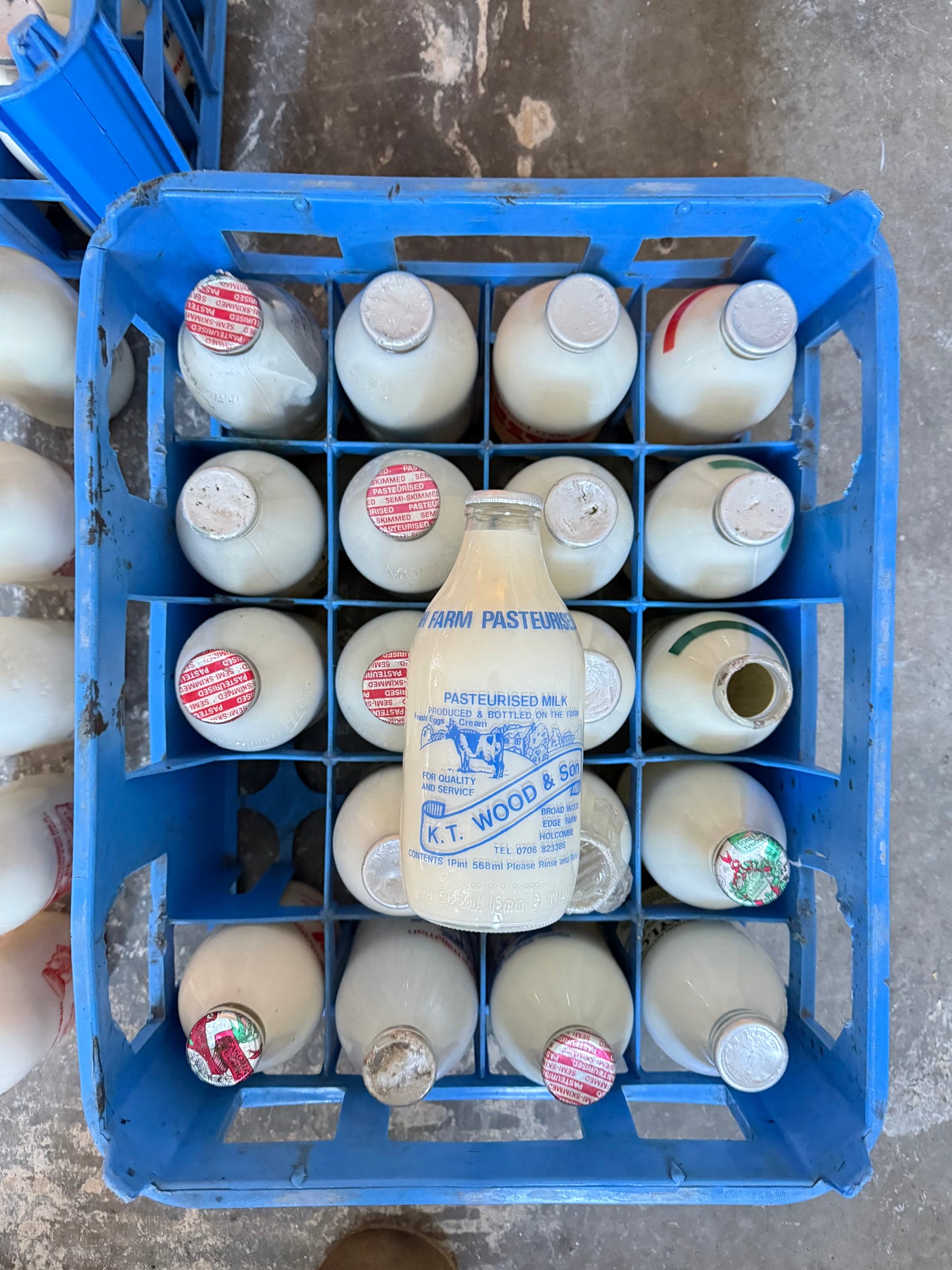 A Collection  of 37 Advertising Milk Bottles in Crates