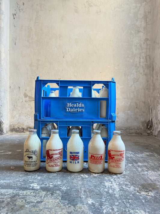 A Collection  of 37 Advertising Milk Bottles in Crates
